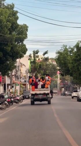 Group in orange shirts rides flatbed truck through Choeng Mon