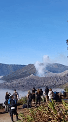 Tourists at Mount Bromo's crater overlook as volcano vents smoke