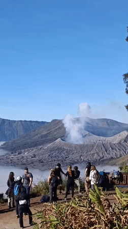 Tourists at Mount Bromo's crater overlook as volcano vents smoke