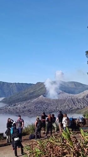 Tourists at Mount Bromo's crater overlook as volcano vents smoke