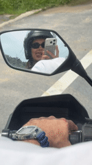 Motorcycle passenger makes playful gestures during ride in Thailand