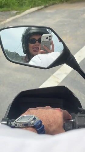 Motorcycle passenger makes playful gestures during ride in Thailand