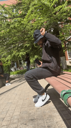 Young man listens to music on park bench in Beijing