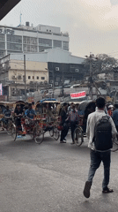 Decorated cycle rickshaws navigate busy Dhaka morning traffic