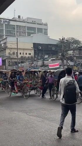 Decorated cycle rickshaws navigate busy Dhaka morning traffic