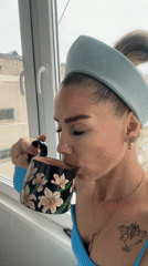 Woman in blue enjoys morning drinks by window in Abakan
