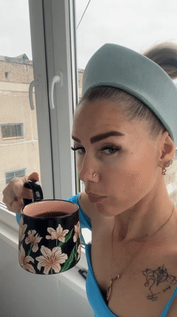 Woman in blue enjoys morning drinks by window in Abakan