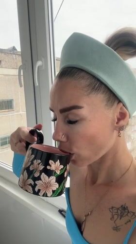 Woman in blue enjoys morning drinks by window in Abakan