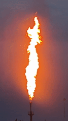 Industrial flare stack burns against twilight sky