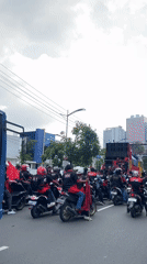 Large street gathering with motorcycles, yellow truck in Surabaya