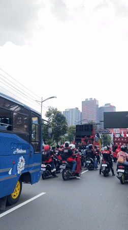 Large street gathering with motorcycles, yellow truck in Surabaya