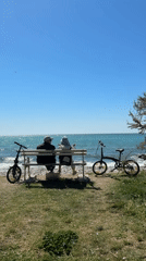 Two people sit on bench overlooking sea in Bar