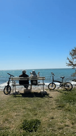 Two people sit on bench overlooking sea in Bar