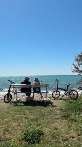 Two people sit on bench overlooking sea in Bar