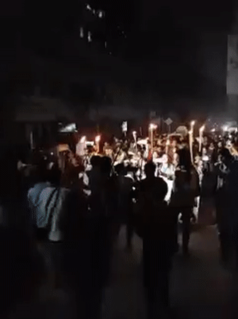 Torchlight procession with Bengali banners held in nighttime Dhaka