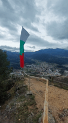 Bulgarian flag waves on hilltop overlooking Devin town