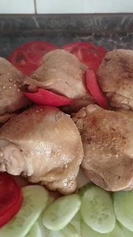 The media file shows a close-up, overhead view of a plate of food. The main subjects are several pieces of cooked chicken, which appear to be chicken thighs, arranged on a white plate. They are golden brown and lightly seasoned. Surrounding the chicken are slices of fresh vegetables: red tomato slices and green cucumber slices. A few thin slices of red bell pepper are also interspersed among the chicken pieces.

The overall impression is of a home-cooked meal, likely prepared and served at home. The lighting suggests it's indoors. There are no people visible in the frame. The background is slightly out of focus but appears to be a kitchen counter with some tile work.

The activity taking place is simply the presentation of food. No actions are being performed on the food at this moment. The notable details are the appetizing appearance of the chicken and the fresh vegetables, indicating a meal ready to be eaten. The time of day is not explicitly indicated, but the lighting is neutral. The location context of Horenka, Ukraine, suggests this is a meal prepared in that region. There is no visible text in the media file. The emotions conveyed are those associated with enjoying a meal – perhaps hunger, satisfaction, or comfort.