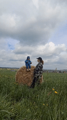 Child sits on hay bale in Russian field