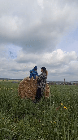 Child sits on hay bale in Russian field