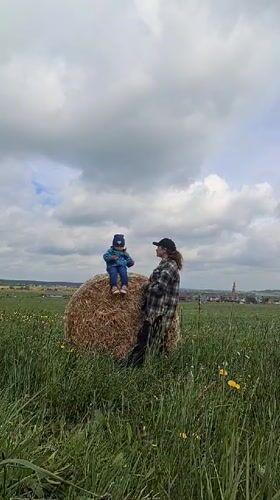 Child sits on hay bale in Russian field