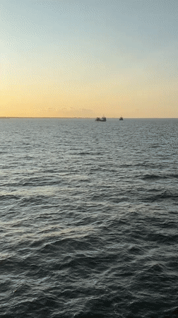 Ferry crossing Denmark at sunrise, vehicles loaded on deck.
