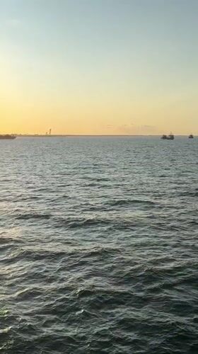 Ferry crossing Denmark at sunrise, vehicles loaded on deck.