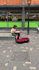 Handpan player busking outside a green storefront