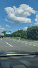 Highway drive past a Ukrainian-themed billboard under sunny skies.