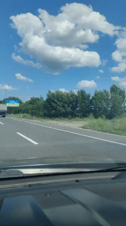 Highway drive past a Ukrainian-themed billboard under sunny skies.