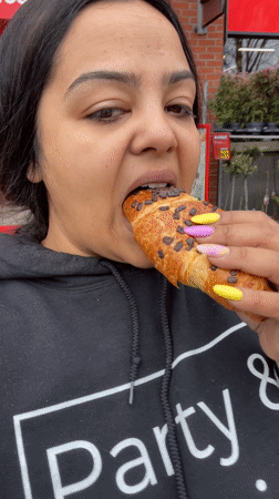 Woman enjoys chocolate croissant outdoors in Dronten