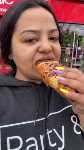 Woman enjoys chocolate croissant outdoors in Dronten