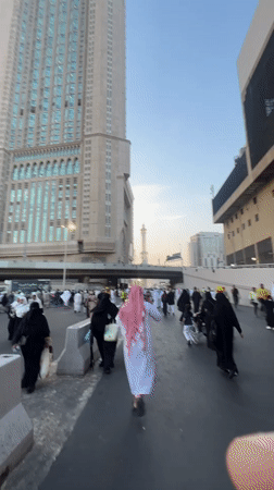 Crowds move through Mecca streets near a mosque minaret