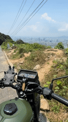 Person overlooks Đà Nẵng cityscape from hillside with motorbike