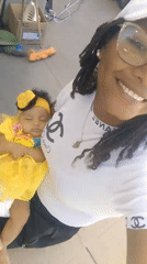 Woman smiles while holding sleeping infant in selfie