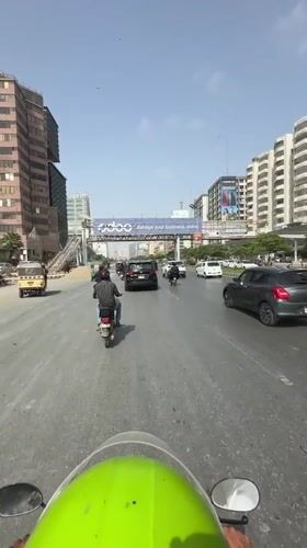 Motorcycle POV through busy Karachi city traffic on a sunny day