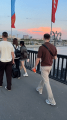 Four people cross flag-lined bridge in afternoon gathering