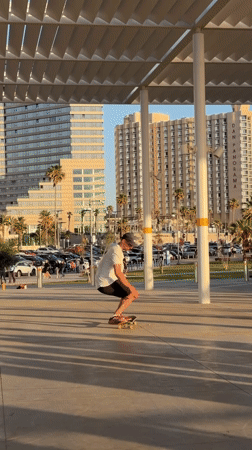 Skateboarder performs trick under covered walkway in Tel Aviv