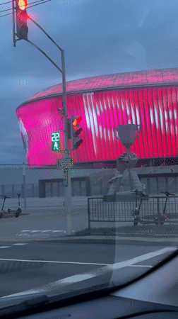Illuminated stadium seen from car on rainy Minsk evening