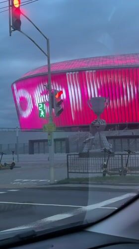 Illuminated stadium seen from car on rainy Minsk evening