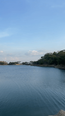 Woman points across lake toward hills in Tinaquillo, Venezuela