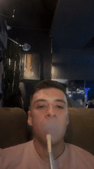Young adult smokes hookah at indoor establishment