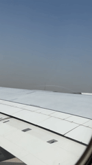 Passenger films Dubai skyline from airplane window on hazy day