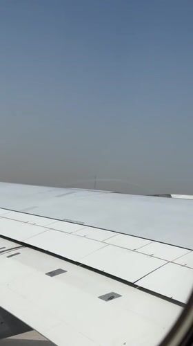 Passenger films Dubai skyline from airplane window on hazy day