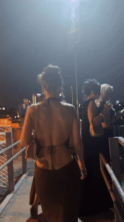Women in evening wear stroll Belgrade waterfront promenade at night