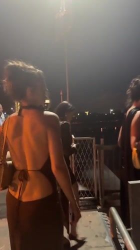 Women in evening wear stroll Belgrade waterfront promenade at night