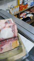 Person handles mixed Nigerian currency at counter with paperwork