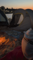 Campfire and tents on a Bulgarian beach at dusk