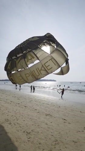 Parasailing operator sets up equipment on sunny Phuket beach