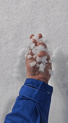 Person holds snow while wearing blue jacket in Russia