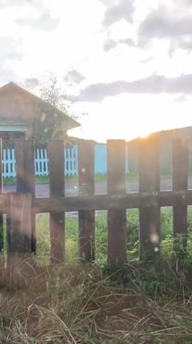 Wooden fence and rural house at sunset, two angles